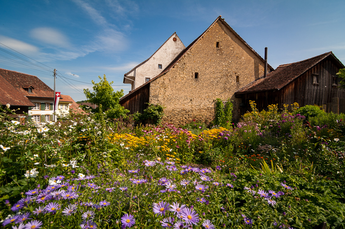 Altes Bauernhaus im Dorf Rünenberg, Baselland – mit gepflegtem Blumengarten im Vordergrund